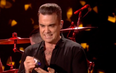 Watch a grimacing Robbie Williams use hand-sanitiser after touching audience at NYE gig