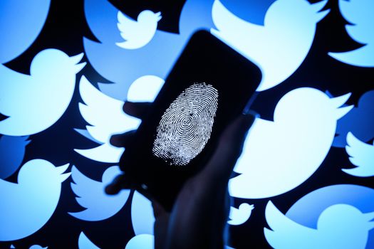 LONDON, ENGLAND - AUGUST 09: In this photo illustration, a thumbprint is displayed on a mobile phone as the logo for the Twitter social media network is projected onto a screen on August 09, 2017 in London, England. With around 328 million users worldwide, Twitter has gone from a small start-up in for the public 2006 to a broadcast tool of politicians and corporations in 2017. (Photo by Leon Neal/Getty Images)