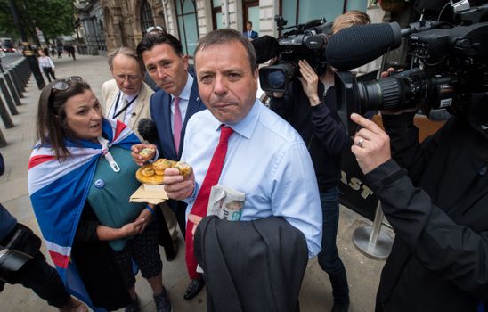 LONDON, ENGLAND - JUNE 12: Leave.EU backer Arron Banks eats a pork pie handed to him by an anti-Brexit demonstrator as he arrives to give evidence to the fake news select committee at Portcullis House on June 12, 2018 in London, England. The Digital, Culture, Media and Sport Committee are questioning Arron Banks and Andy Wigmore, of the pro-Brexit Leave.EU, as part of its inquiry into fake news. British Newspapers have revealed a series of meetings with Russia's UK Ambassador in the lead up to the Brexit Referendum. (Photo by Chris J Ratcliffe/Getty Images)