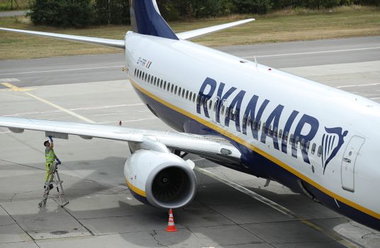 SCHOENEFELD, GERMANY - AUGUST 10: A ground crew worker stands on a ladder at a RyanAir passenger plane at Schoenefeld Airport near Berlin during a 24-hour strike by RyanAir pilots on August 10, 2018 in Schoenefeld, Germany. RyanAir pilots in Germany, Ireland, Sweden, Belgium and Holland are taking part in the strike over demands for better pay and working conditions. (Photo by Sean Gallup/Getty Images)