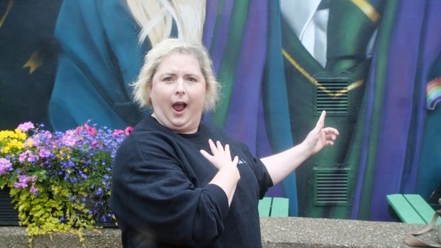 Siobhan McSweeney, who plays Sister Michael in Derry Girls, stands in front of their mural in Derry.