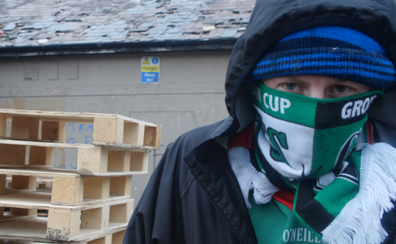 A child with their face covered looks down the camera in Derry's bogside.