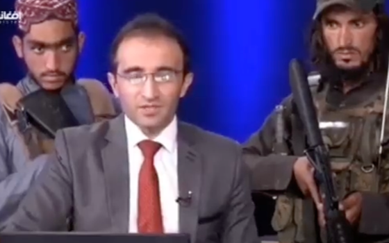 Afghan TV presenter speaks with eight armed Taliban soliders behind him