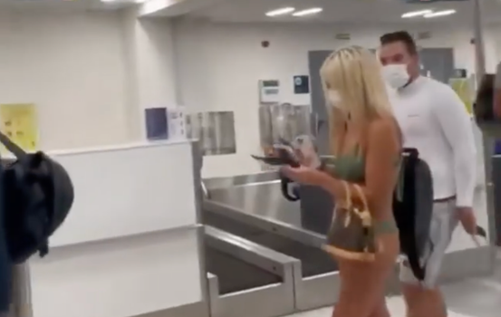 woman walks through airport in just bikini and facemask